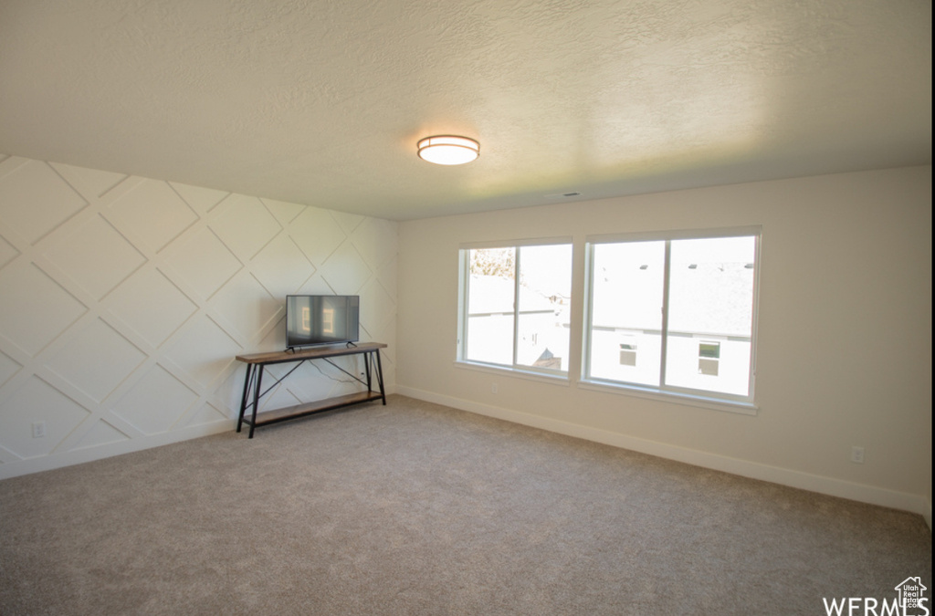 Unfurnished living room with carpet floors and a textured ceiling