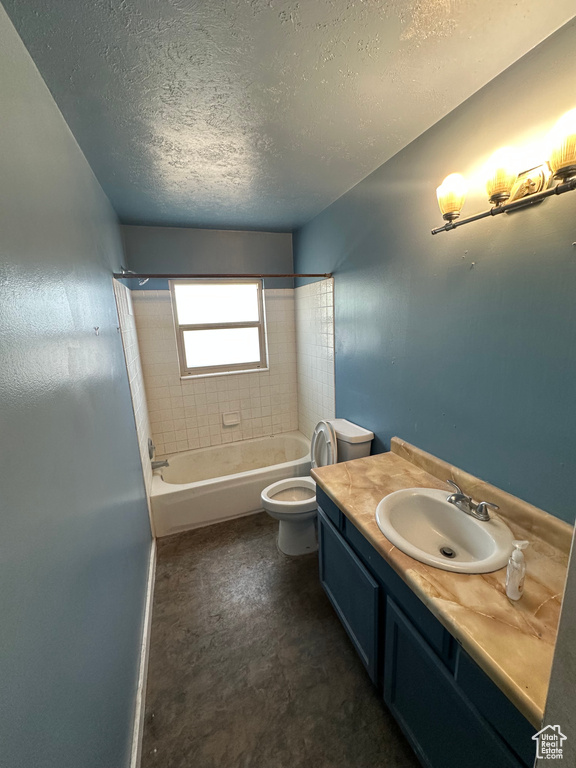 Bathroom with a textured ceiling, vanity, and shower / washtub combination