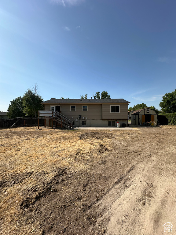 Back of house featuring a storage shed and stairs