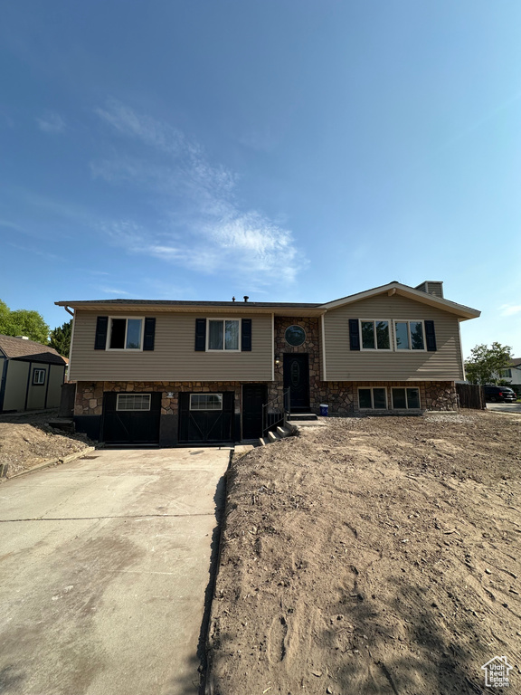 Split foyer home featuring a storage unit and stone siding