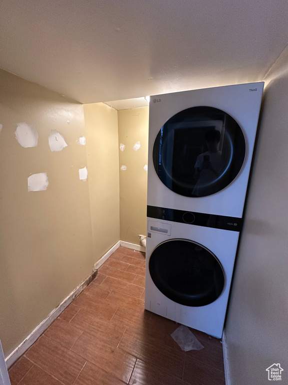 Laundry room with stacked washer and clothes dryer and baseboards