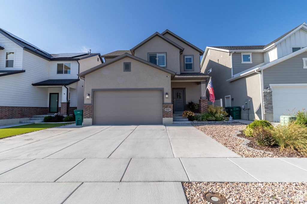 View of front of property featuring stucco siding, an attached garage, brick siding, and concrete driveway