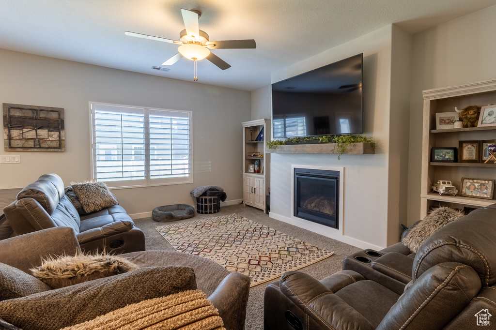 Living area featuring ceiling fan, a glass covered fireplace, and carpet floors