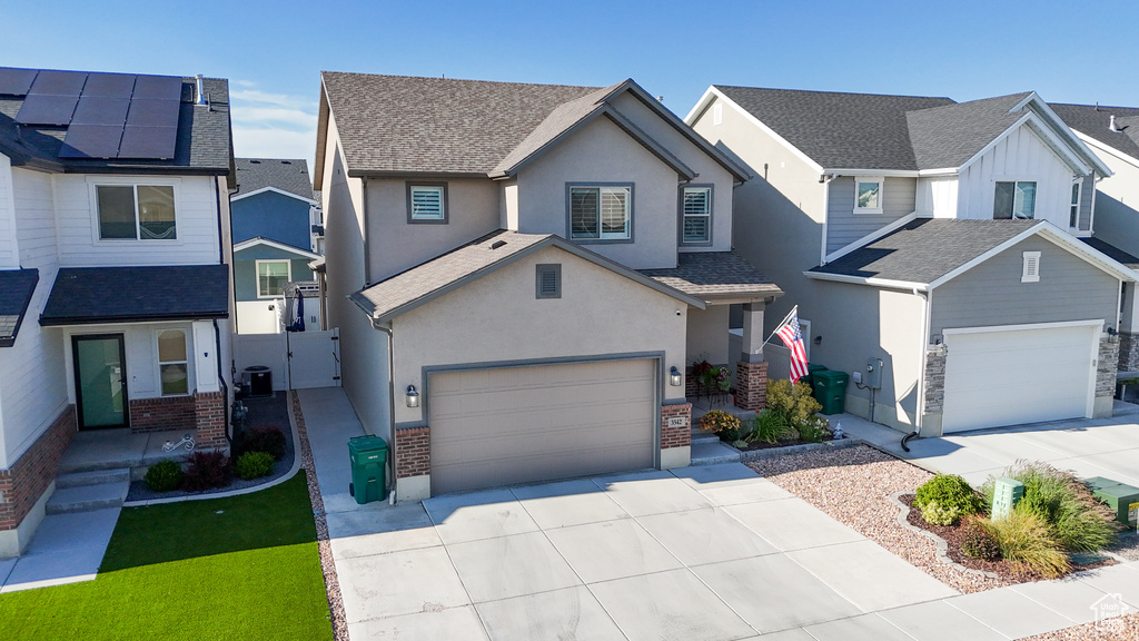 View of front of house with driveway, stucco siding, a gate, and a residential view