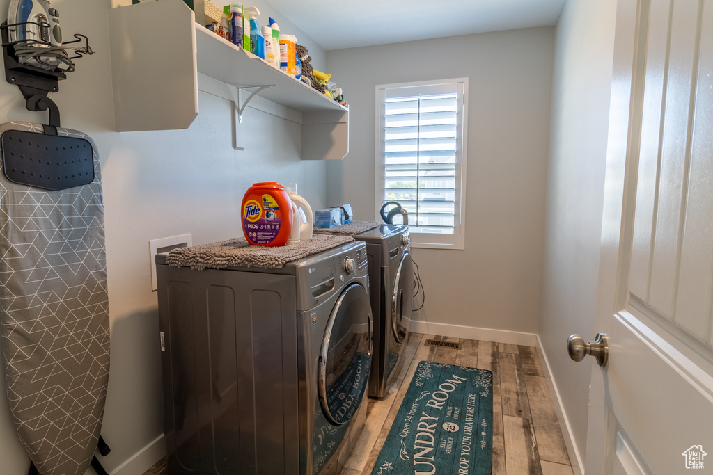 Laundry room with washing machine and dryer and wood finished floors