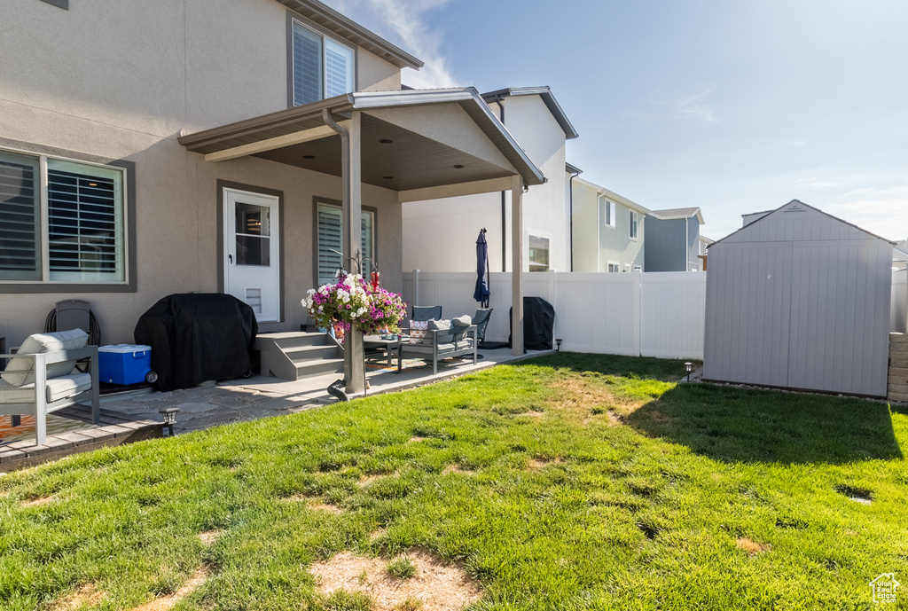 Rear view of house featuring a storage shed, stucco siding, and a patio