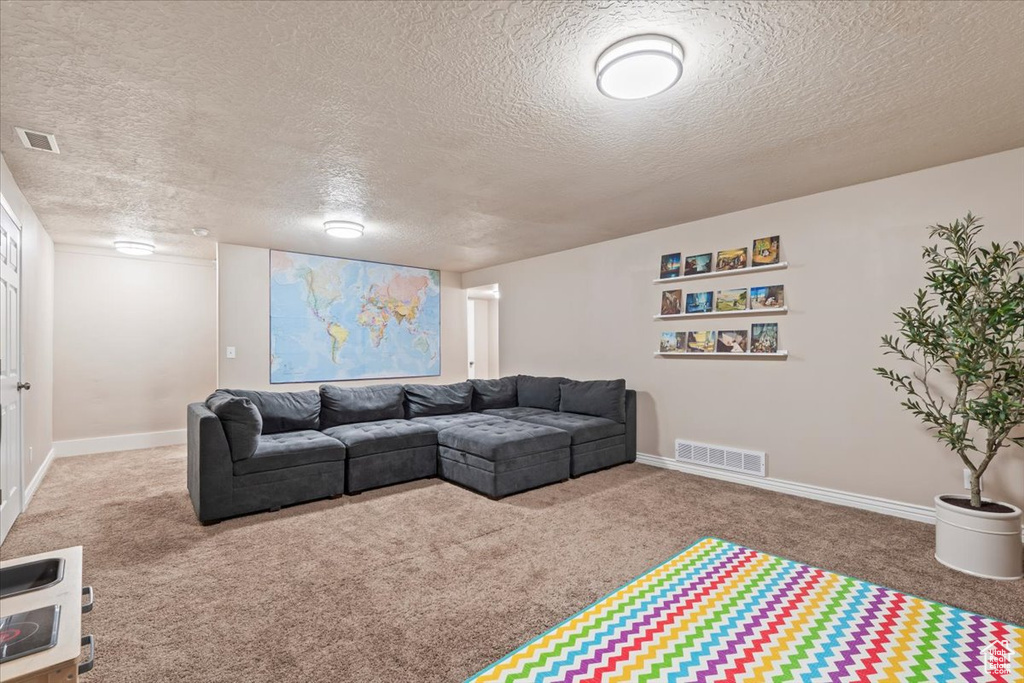 Carpeted living area featuring a textured ceiling and baseboards