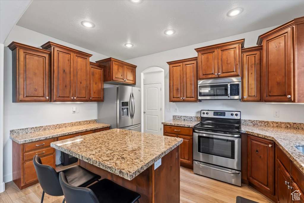 Kitchen featuring appliances with stainless steel finishes, a breakfast bar area, light wood-style floors, a center island, and recessed lighting