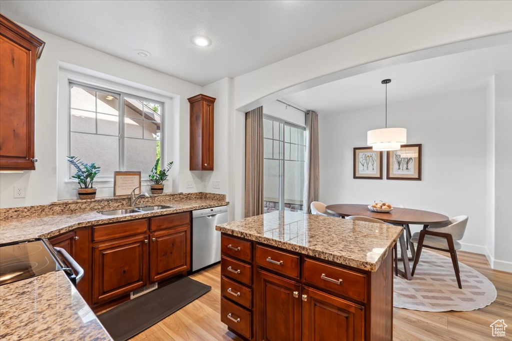 Kitchen featuring dishwasher, light wood-style flooring, arched walkways, pendant lighting, and a kitchen island