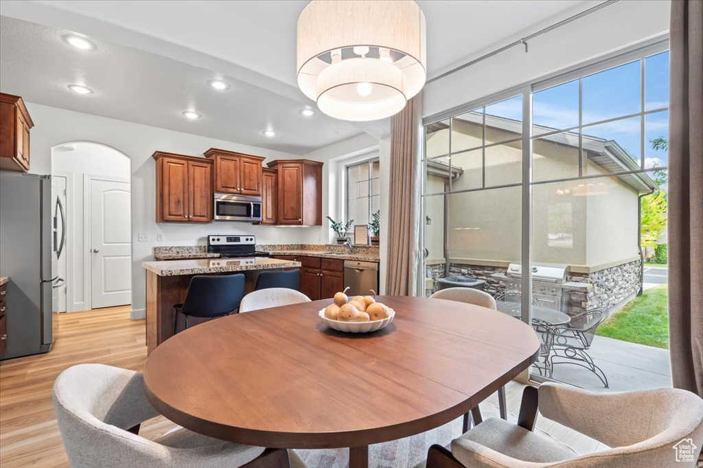 Dining area with recessed lighting, light wood-style floors, and arched walkways