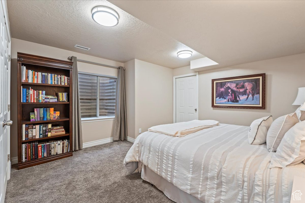 Carpeted bedroom with baseboards and a textured ceiling