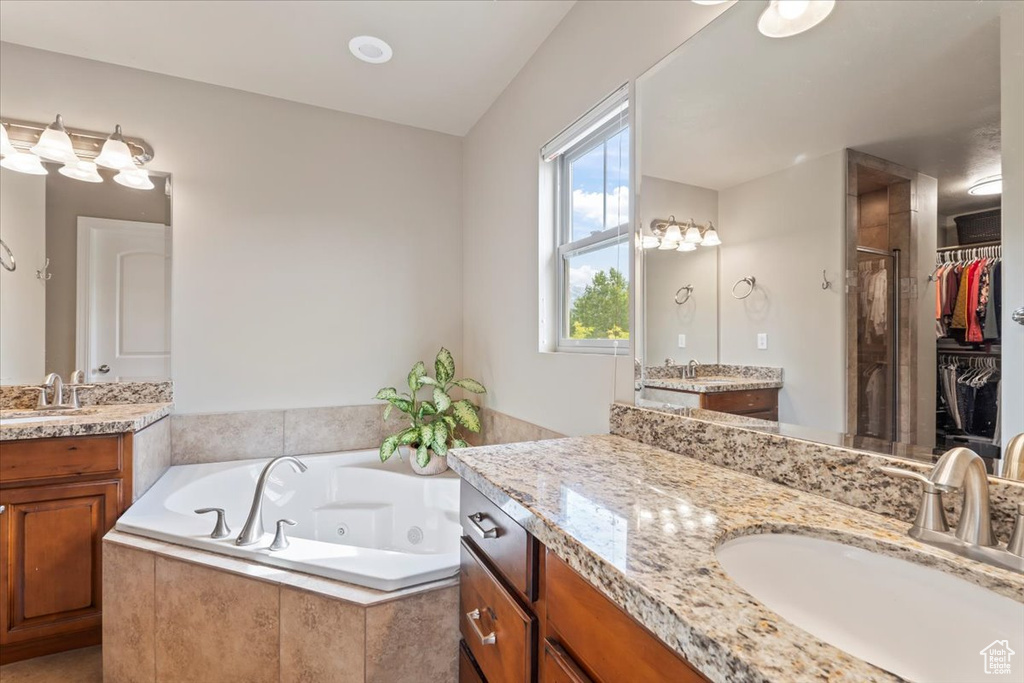 Bathroom with a stall shower, a tub with jets, and two vanities