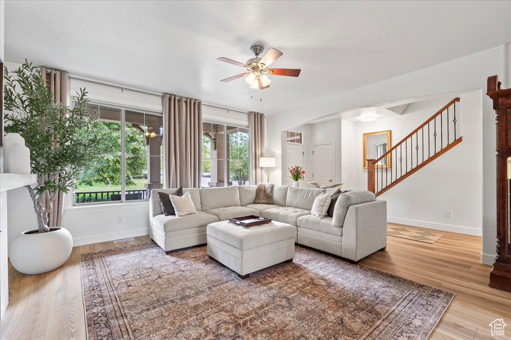 Living room featuring ceiling fan, stairway, wood finished floors, and arched walkways