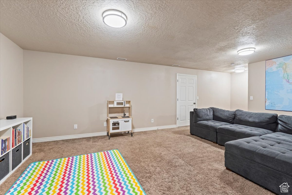 Carpeted living area with a textured ceiling and baseboards