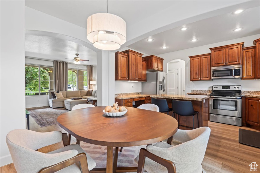 Dining room featuring light wood-style floors, arched walkways, recessed lighting, and a ceiling fan
