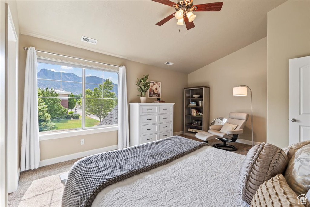 Carpeted bedroom with a mountain view, vaulted ceiling, and ceiling fan