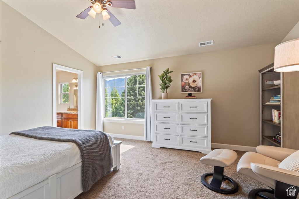 Bedroom with light carpet, vaulted ceiling, a ceiling fan, and connected bathroom
