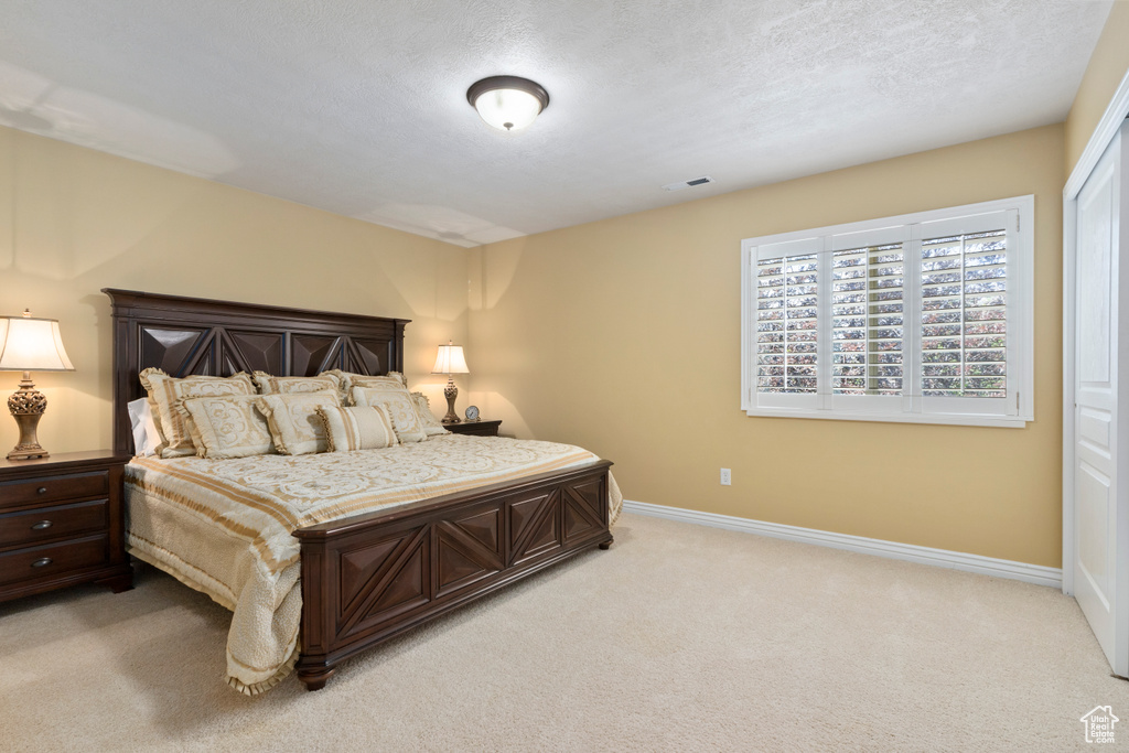 Bedroom with light colored carpet and a textured ceiling