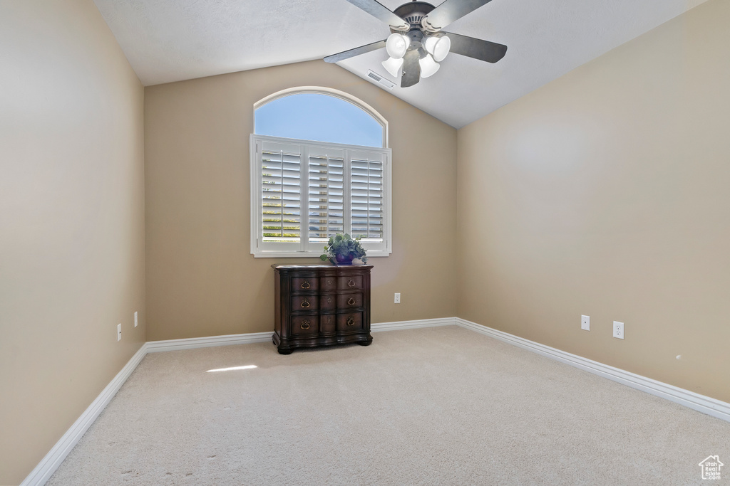 Empty room featuring a ceiling fan, carpet, and lofted ceiling