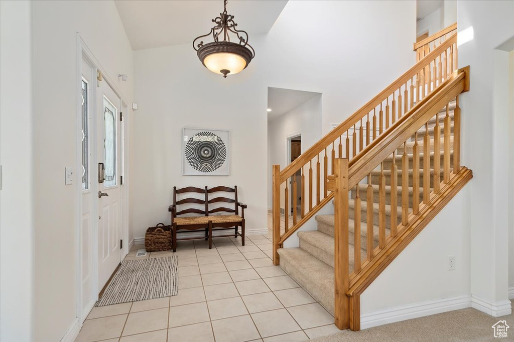 Entryway featuring stairway, a high ceiling, and light tile patterned floors