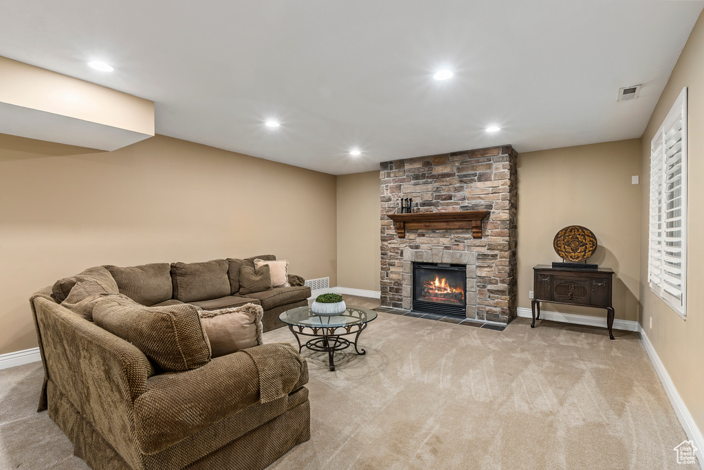 Living room with carpet flooring, recessed lighting, and a stone fireplace