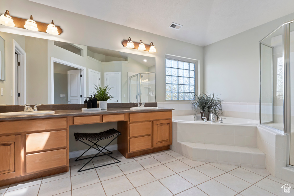 Bathroom with double vanity, a shower stall, a garden tub, and tile patterned flooring
