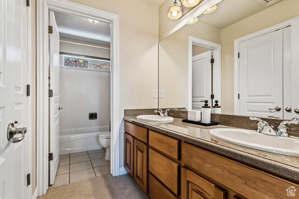 Bathroom featuring double vanity, tile patterned floors, and a bathtub
