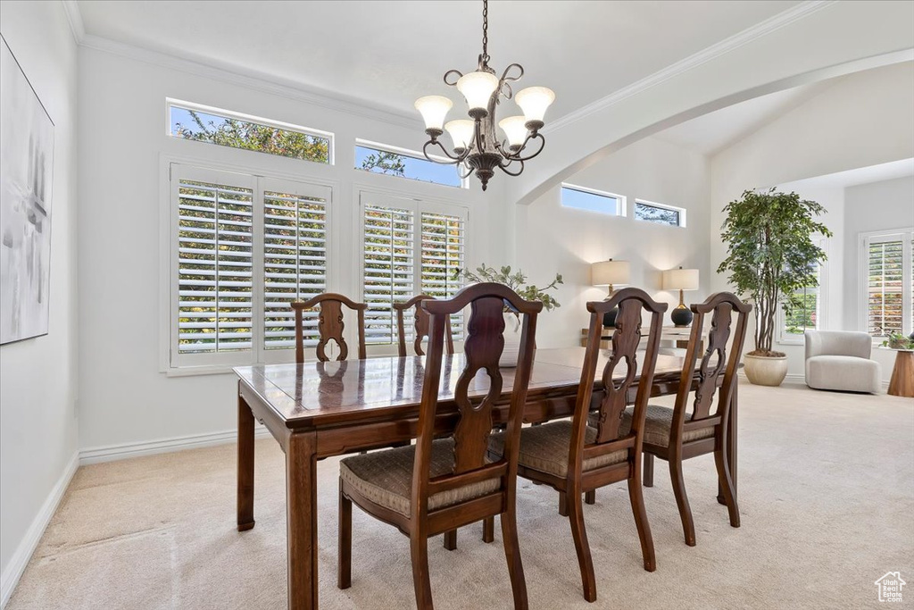 Dining area featuring light colored carpet, a chandelier, plenty of natural light, and ornamental molding