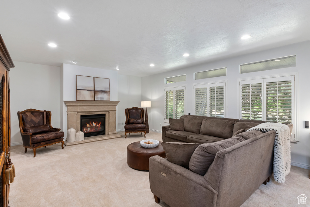 Living room with a glass covered fireplace, recessed lighting, light carpet, and healthy amount of natural light