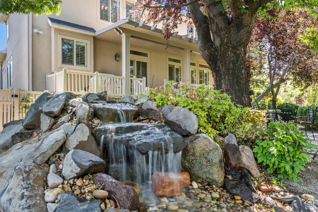 Exterior view of stucco siding, a small pond, and decorative columns
