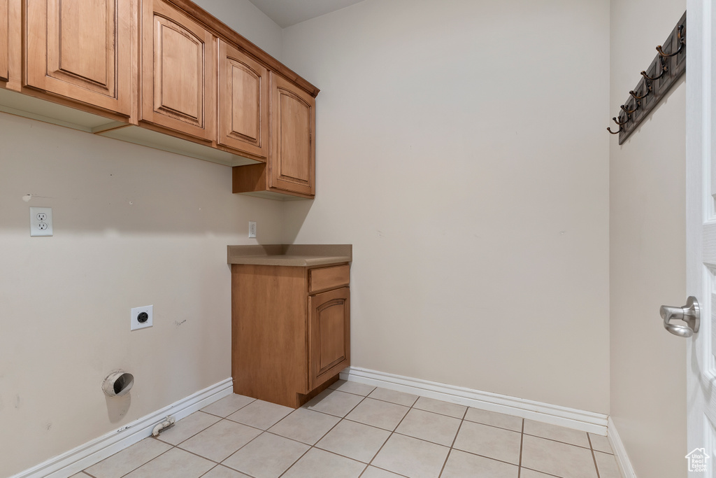 Laundry room with hookup for an electric dryer, light tile patterned flooring, and cabinet space