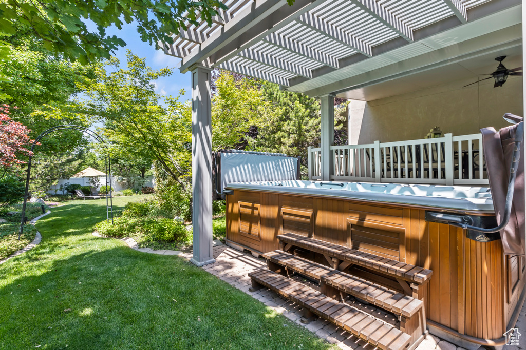 Wooden terrace featuring a hot tub, a yard, ceiling fan, and a pergola