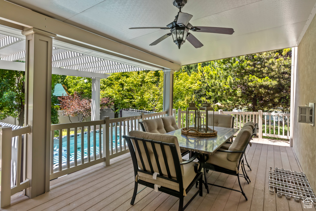 Wooden deck featuring a pergola, a ceiling fan, and outdoor dining area