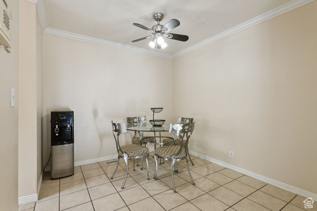 Dining area with crown molding, ceiling fan, and light tile patterned flooring