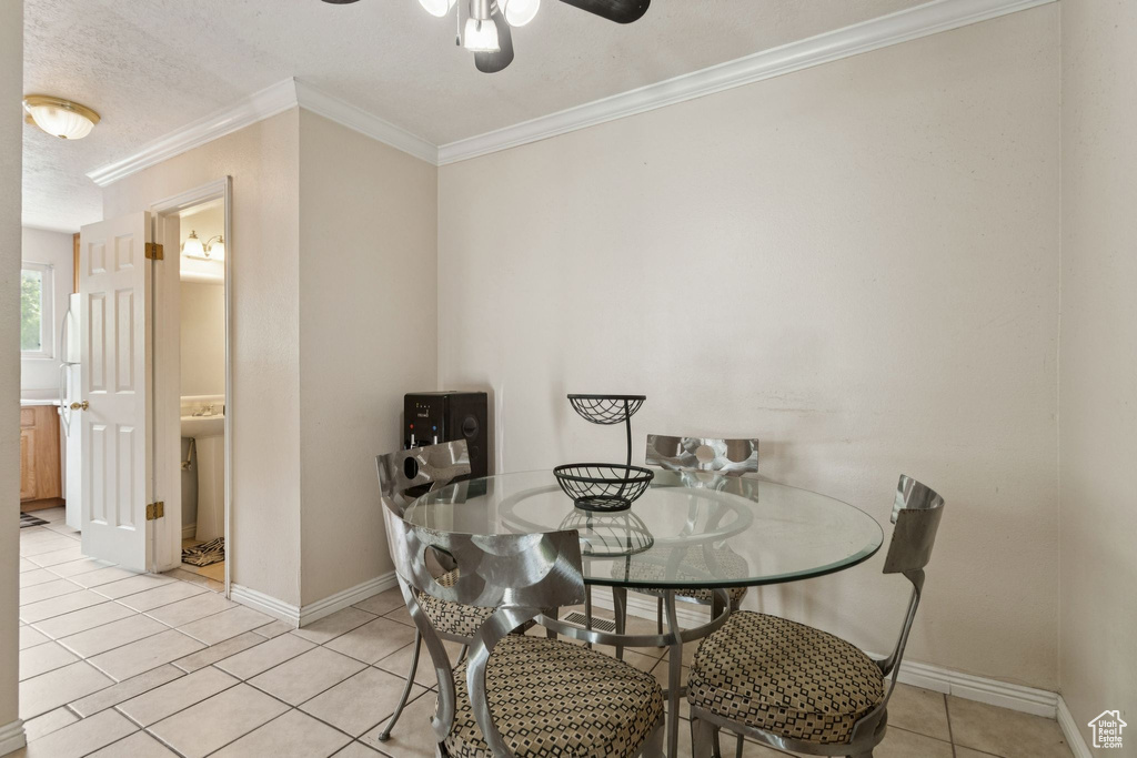 Dining room with a ceiling fan, light tile patterned floors, ornamental molding, and a textured ceiling