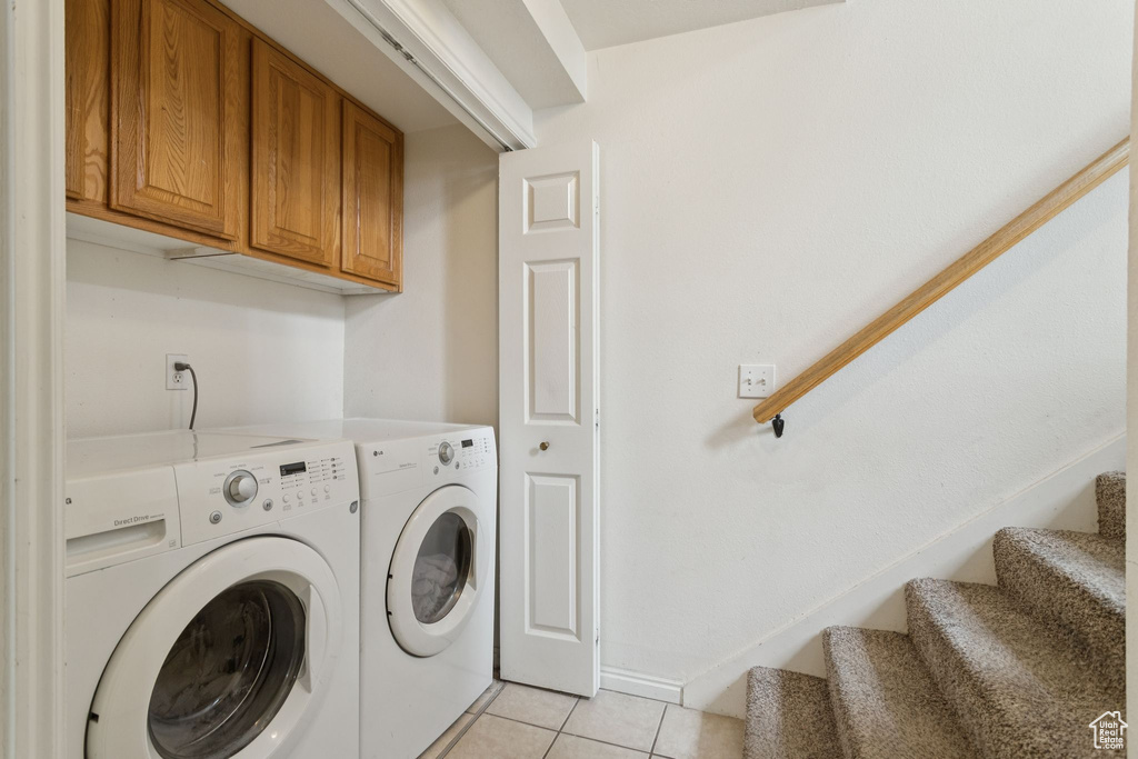 Laundry area with light tile patterned flooring, separate washer and dryer, and cabinet space