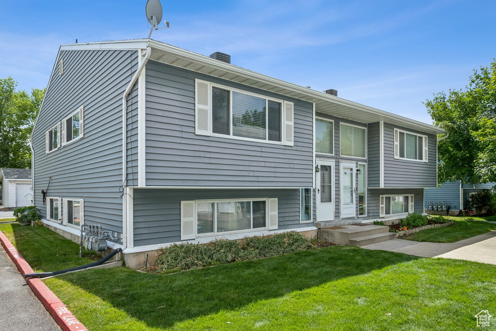 Bi-level home featuring a front yard and a chimney