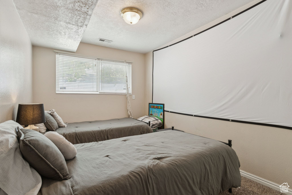 Carpeted bedroom featuring a textured ceiling and baseboards