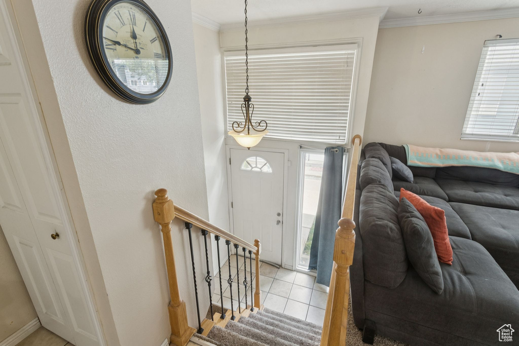 Foyer entrance featuring crown molding, plenty of natural light, light tile patterned floors, and stairs