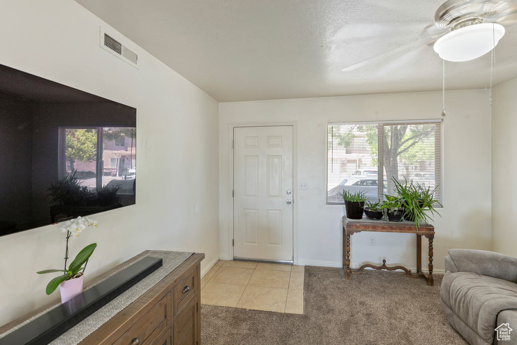 Foyer with light colored carpet, plenty of natural light, a ceiling fan, and light tile patterned floors