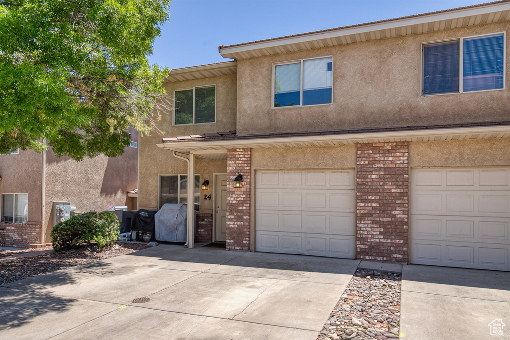 View of front of property with concrete driveway, brick siding, stucco siding, and an attached garage