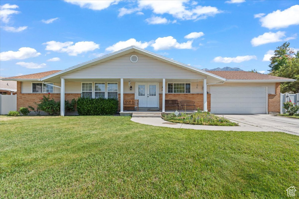 Single story home featuring brick siding, a garage, driveway, and a front lawn
