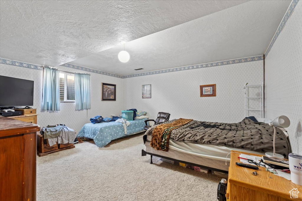 Bedroom with carpet, a textured ceiling, and wallpapered walls