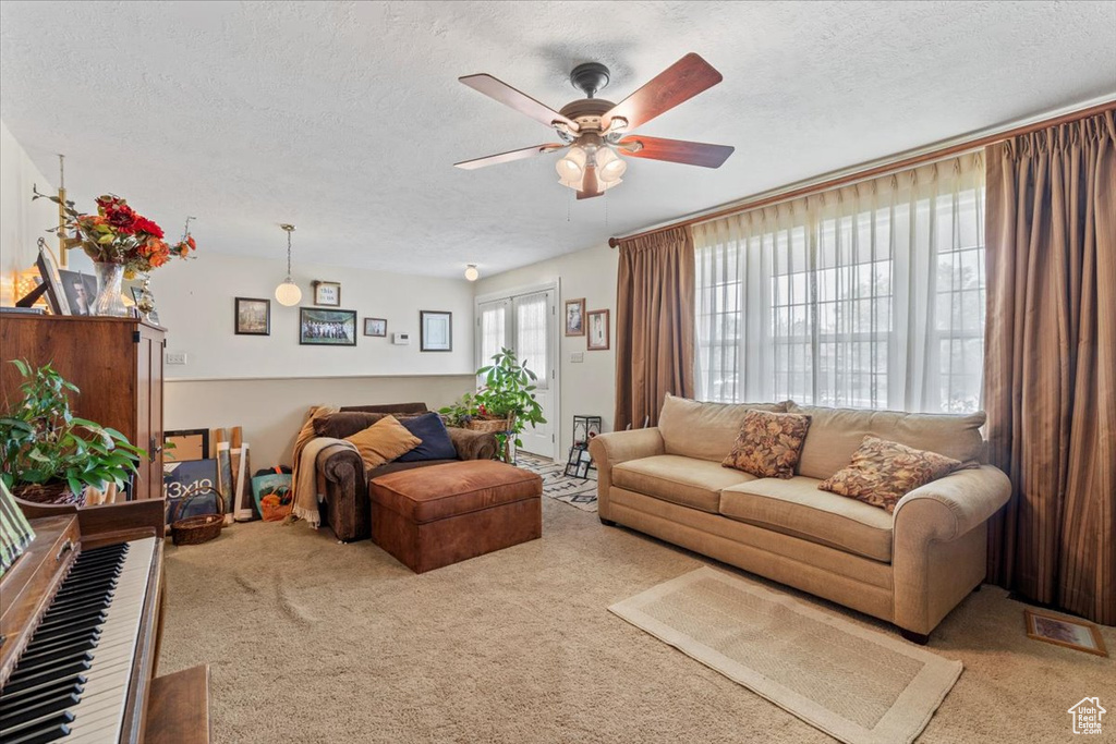 Carpeted living area with a textured ceiling and ceiling fan