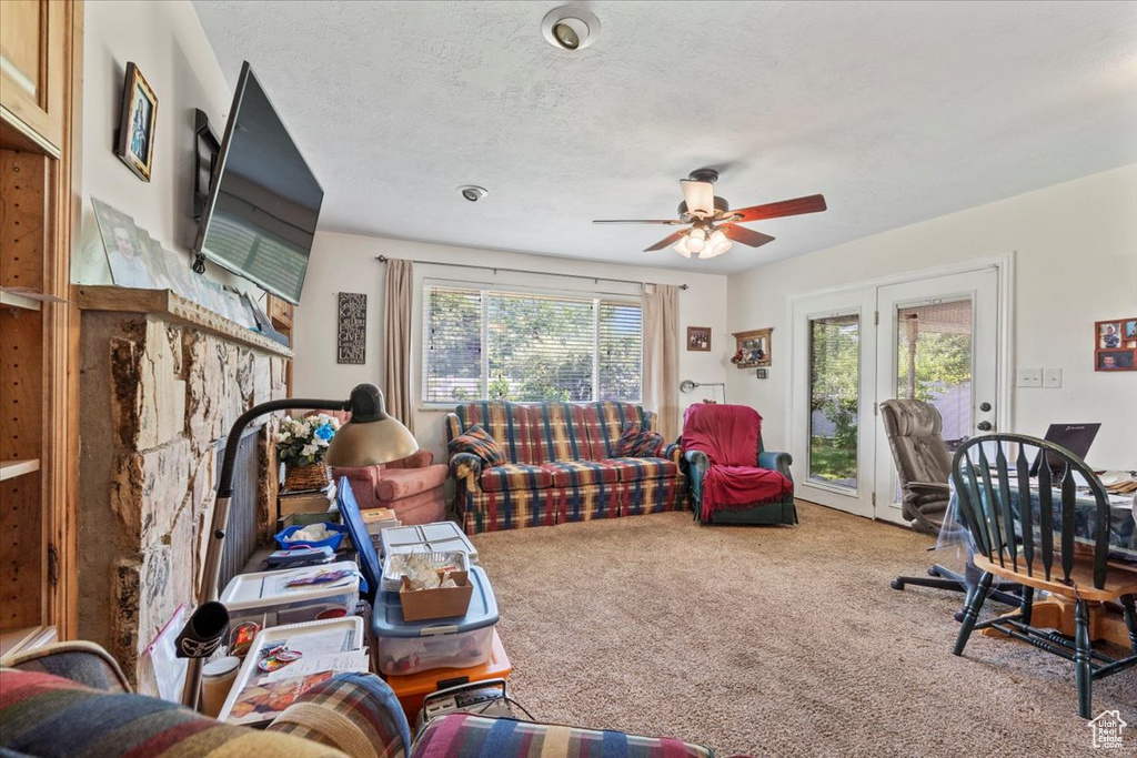 Carpeted living area featuring a ceiling fan and a textured ceiling