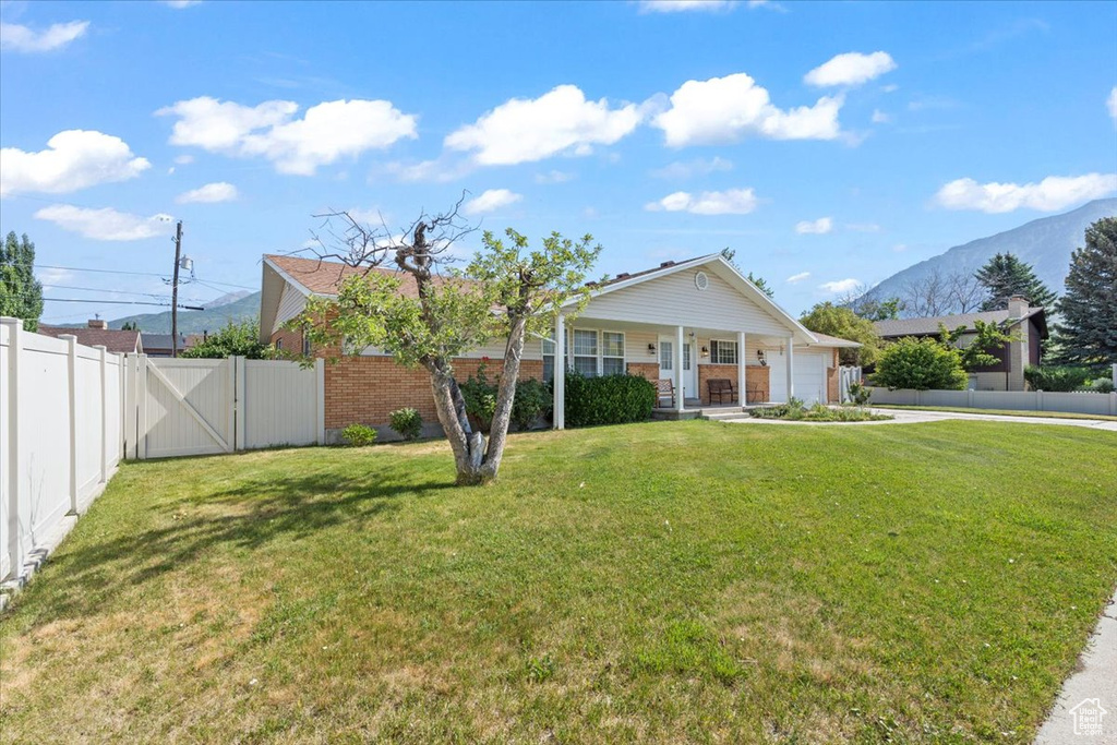 Ranch-style house with an attached garage, a gate, concrete driveway, covered porch, and a mountain view