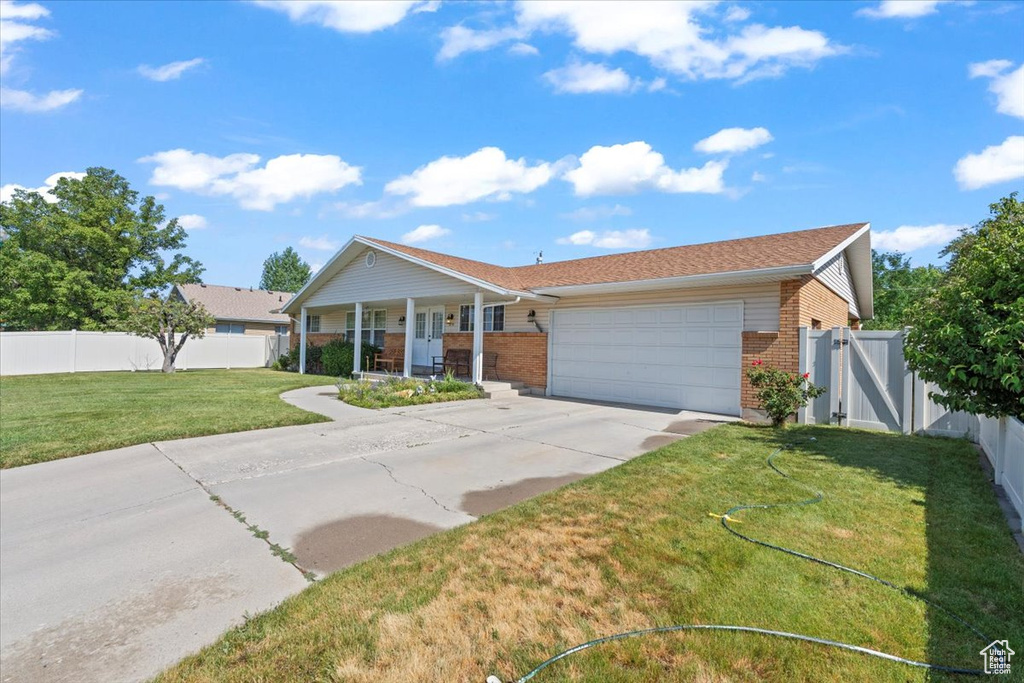 Single story home featuring brick siding, an attached garage, a porch, and concrete driveway