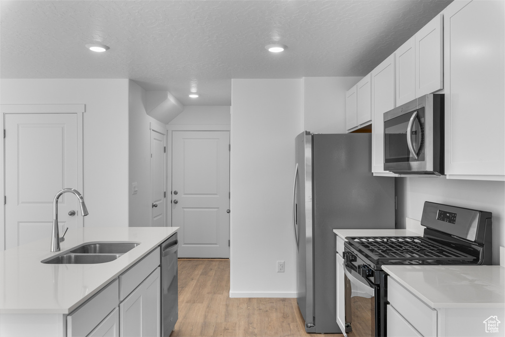 Kitchen with stainless steel appliances, light countertops, recessed lighting, light wood-style flooring, and white cabinetry
