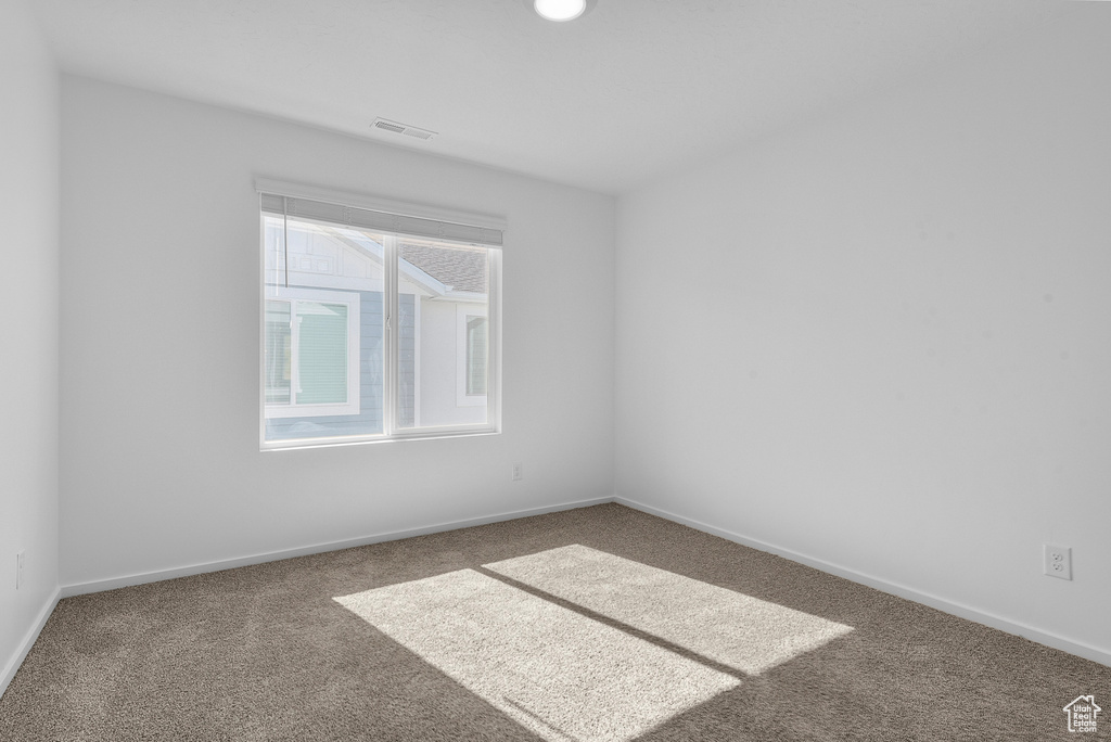 Carpeted spare room featuring baseboards