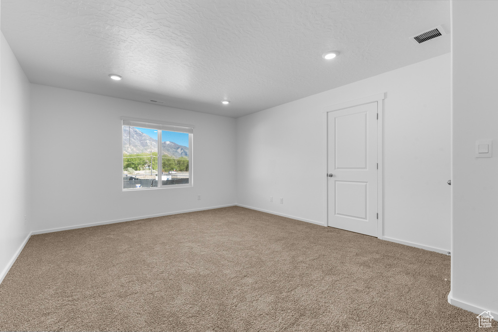 Empty room featuring carpet, a textured ceiling, and recessed lighting